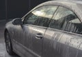 Car wash with soap. Fragment of gray vehicle with active foam. Sunny lighting.