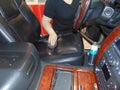 A car wash worker applies a protective conditioner to the leather seat of a car after cleaning it.