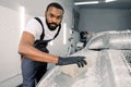 Car washing and detailing concept. Young concentrated African American male worker holding the sponge in hand and Royalty Free Stock Photo