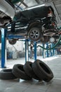 Car wheel and auto on lift, tire service concept Royalty Free Stock Photo