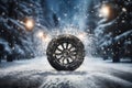 a car wheel on the background of a winter road and a beautiful night landscape, a snow-covered forest with lights, a concept Royalty Free Stock Photo