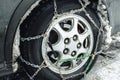 Car wheel with chains. Close-up. Fenders of the car clogged with snow. Snow chains on the car wheel. Safety on winter