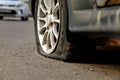 Car wheel with a flat tire on the roadway. Image of an accident, damage, breakdown for illustration on the topic of repair, Royalty Free Stock Photo