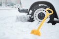 Car wheel in snow and a shovel.