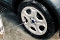 Car wheel washing, detailing concept. Cropped close up image of car cleaning with high pressure water jet, gun. Car rims