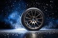 Car wheel with winter tires on dark background during snowy weather. Seasonal wheel changes. Car service.