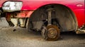 Car without wheels costs on brick, old rusty car brakes in poor condition.