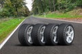 Car wheels set - four car wheels arranged in a row on the asphalt road next to the forest Royalty Free Stock Photo