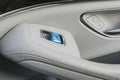 Car white leather interior details of door handle with windows controls and adjustments. Car window controls blue button of modern Royalty Free Stock Photo