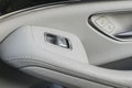 Car white leather interior details of door handle with windows controls and adjustments. Car window controls of modern car Royalty Free Stock Photo