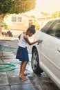 The car will be spotless when shes done. a young girl busy cleaning a car outside.