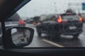 Car window with rain drops window on glass rear view mirror with background blurred. City life in evening in rainy season storm ra Royalty Free Stock Photo