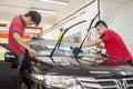 2 Car window tinting specialist attaching Tinting Film to car front windscreen.