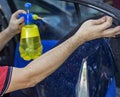 Car window tinting specialist spraying soapy water on vinyl tinting film