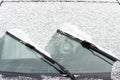 Car windows and wipers covered with snow in winter