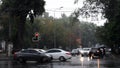 Car windshield view of rain city traffic. Cars move by crossroad while drizzle rain