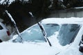 Car windshield with wiper blades cleaned from snow outdoors on winter day