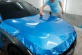 Car wrapping, man with squeegee installs film