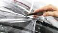 Car wrapping specialist putting vinyl foil or film on car. Protective film. Applying a protective film with tools for work. Car de