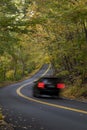 Car zooming down a colorful autumn road Royalty Free Stock Photo