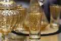 Carafe and several glass glasses on an ornate table in natural daylight.