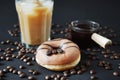 Caramel donut with coffee decor next to a glass of frappuccino with ice and a glass scoop of coffee