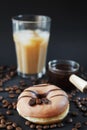 Caramel donut with coffee decor next to a glass of frappuccino with ice and a glass scoop of coffee