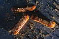 Caramel eclairs with golden sprinkles on dark bakcground.