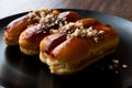 Caramel Eclairs with Hazelnut and cream in black plate.