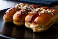 Caramel Eclairs with Hazelnut and cream in black plate.