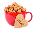 Caramel popcorn in red cup and wooden heart. Royalty Free Stock Photo