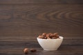 Caramelized almonds in a small white bowl on a wood background Royalty Free Stock Photo