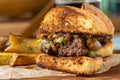 Caramelized onion burger with avocado sauce cut in half, with sauces and french fries on the side Royalty Free Stock Photo