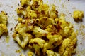 Roasted curried cauliflower on a baking paper covered sheet pan.