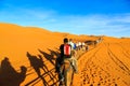 Caravan of camels with tourist in the desert at sunset Royalty Free Stock Photo