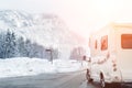 Caravan or campervan turning from road with beautiful mountain alpine landscape on background at cold winter season.Family