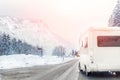 Caravan or campervan turning from road with beautiful mountain alpine landscape on background at cold winter season.Family