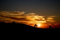 Caravan with people and camels walking over a hill in a desert during the orange sunset Royalty Free Stock Photo