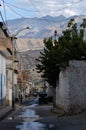 Caraz, Peru, July 19, 2010:  typical street of Peruvian town with motorcycle car, wall and trees,  and wet ground with mountains Royalty Free Stock Photo