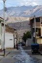 Caraz, Peru, July 19, 2010:  typical street of Peruvian town with motorcycle car and wet ground with mountains in the background Royalty Free Stock Photo