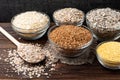 Carbohydrates. Various grain flakes in bowls on wooden. Oat, corn, rice, buckwheat, rye and wheat flakes. Royalty Free Stock Photo