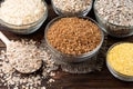 Carbohydrates. Various grain flakes in bowls on wooden. Oat, corn, rice, buckwheat, rye and wheat flakes. Royalty Free Stock Photo