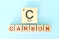 Carbon chemical element symbol with atomic mass and atomic number in wooden blocks flat lay composition.