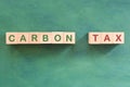 Carbon CO2 emission taxation concept. Carbon tax word in wooden blocks with increasing stack of coins.