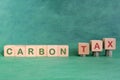 Carbon CO2 emission taxation concept. Carbon tax word in wooden blocks with increasing stack of coins.