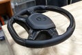 Carbon steering wheel of a black car in the workshop tightened and stitched perforated with natural leather close up with the