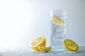 Carbonated soda water with ice cubes and lemon in a drinking glass, refreshing drink against a light gray background, copy space, Royalty Free Stock Photo