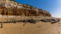 A carcass of a shipwreck on Old Hunstanton Beach resting beneath the white, red and orange stratified cliffs in UK