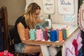 Woman with sewing machine embroidering the first name on fabric for tourists in the street