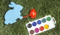 Card bunny with marker on it`s hand, painting egg into red. Royalty Free Stock Photo